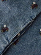 NMFROBERTA Robe chasuble en jean brodée de fleurs fille — Lil' Atelier — Dark Blue Denim — détail de la broderie et de l'ouverture de poche latérale 7 | Appart 17 Bruxelles