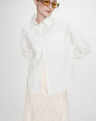 Valerie Chemise oversize en coton à nouer dans le dos — Grace & Mila — Ivoire — Portée de face, plan rapproché : chemise entrouverte sur une jupe longue en dentelle écrue | Appart 17 Bruxelles