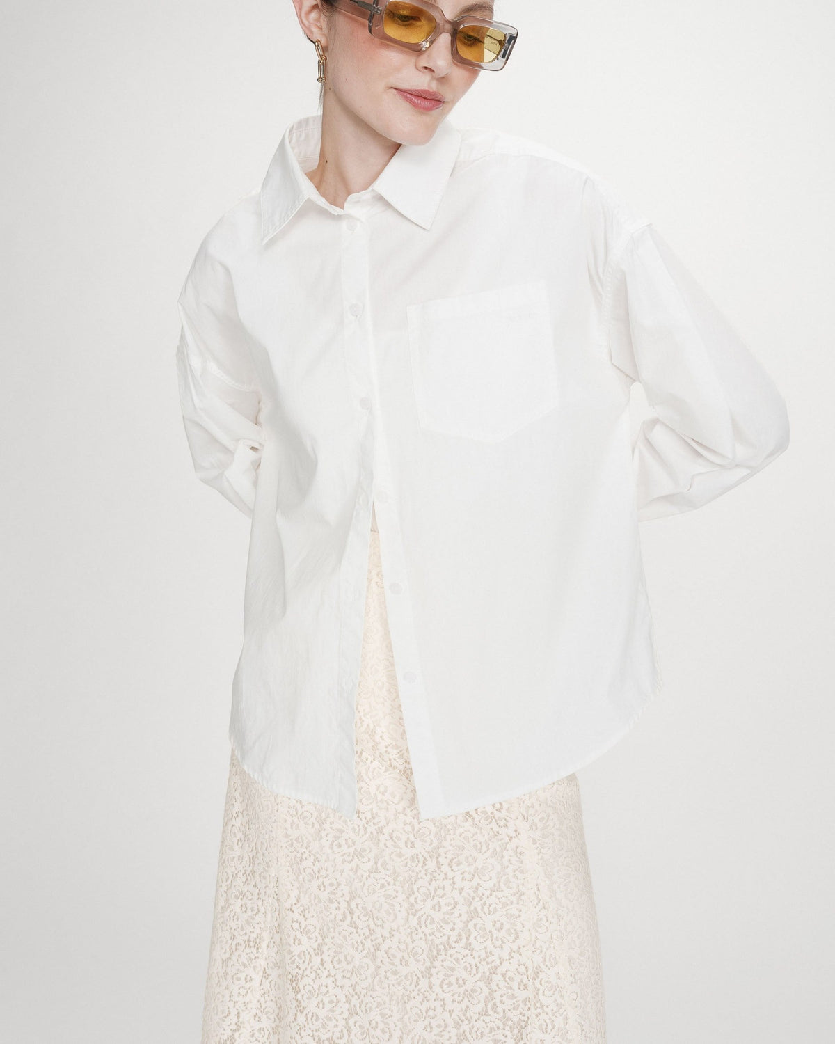 Valerie Chemise oversize en coton à nouer dans le dos — Grace & Mila — Ivoire — Portée de face, plan rapproché : chemise entrouverte sur une jupe longue en dentelle écrue | Appart 17 Bruxelles