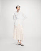 Valerie Chemise oversize en coton à nouer dans le dos — Grace & Mila — Ivoire — Portée en pied de face : chemise entrouverte, jupe longue en dentelle et mocassins clairs 3 | Appart 17 Bruxelles