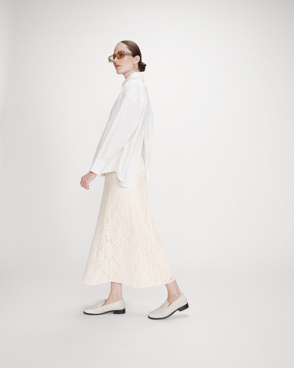 Valerie Chemise oversize en coton à nouer dans le dos — Grace & Mila — Ivoire — Portée en pied de profil, en marche : volume oversize, poignet boutonné et fente du dos 4 | Appart 17 Bruxelles